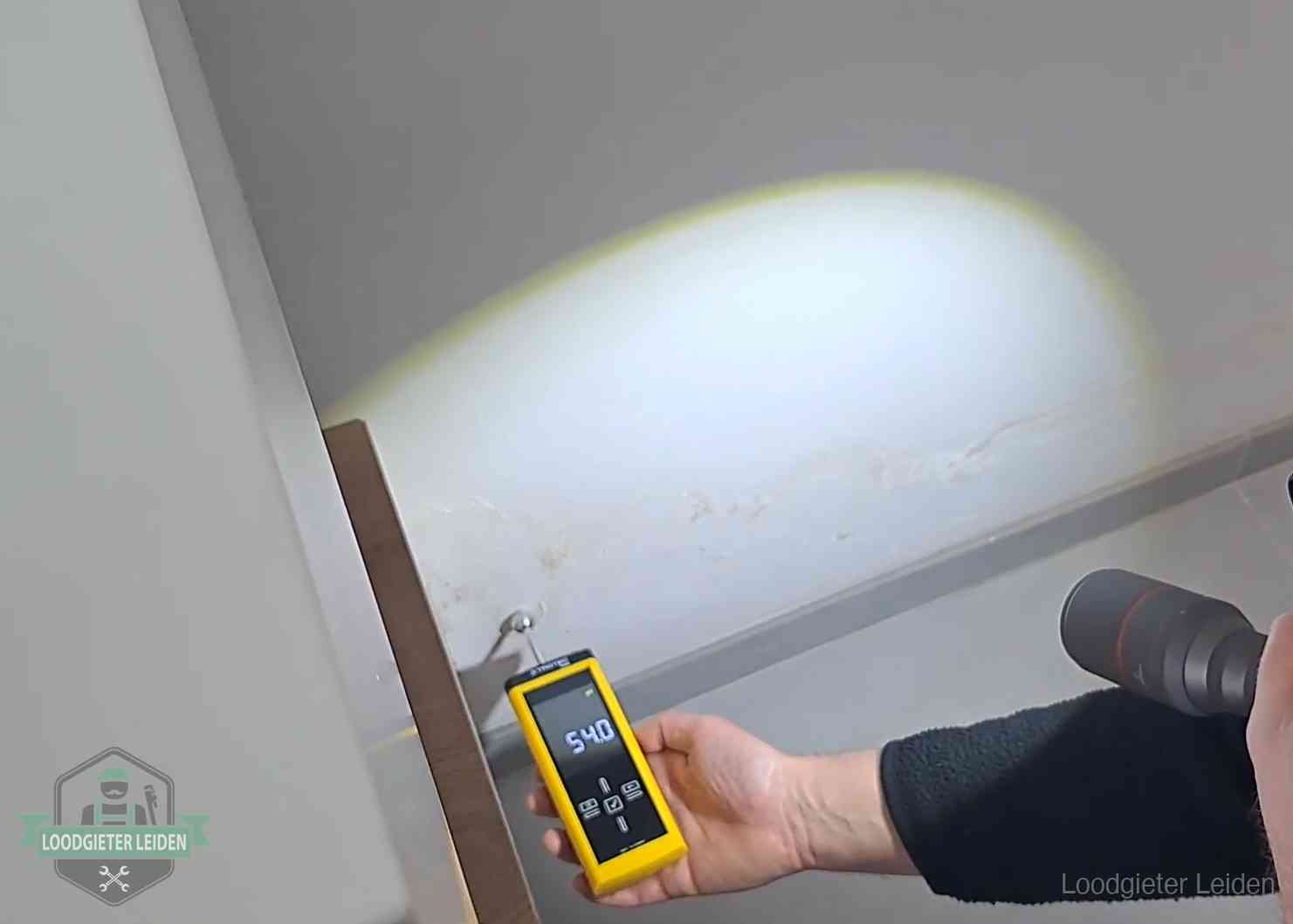Vochtmeter tegen een natte wand met lekkagesporen in Leiden