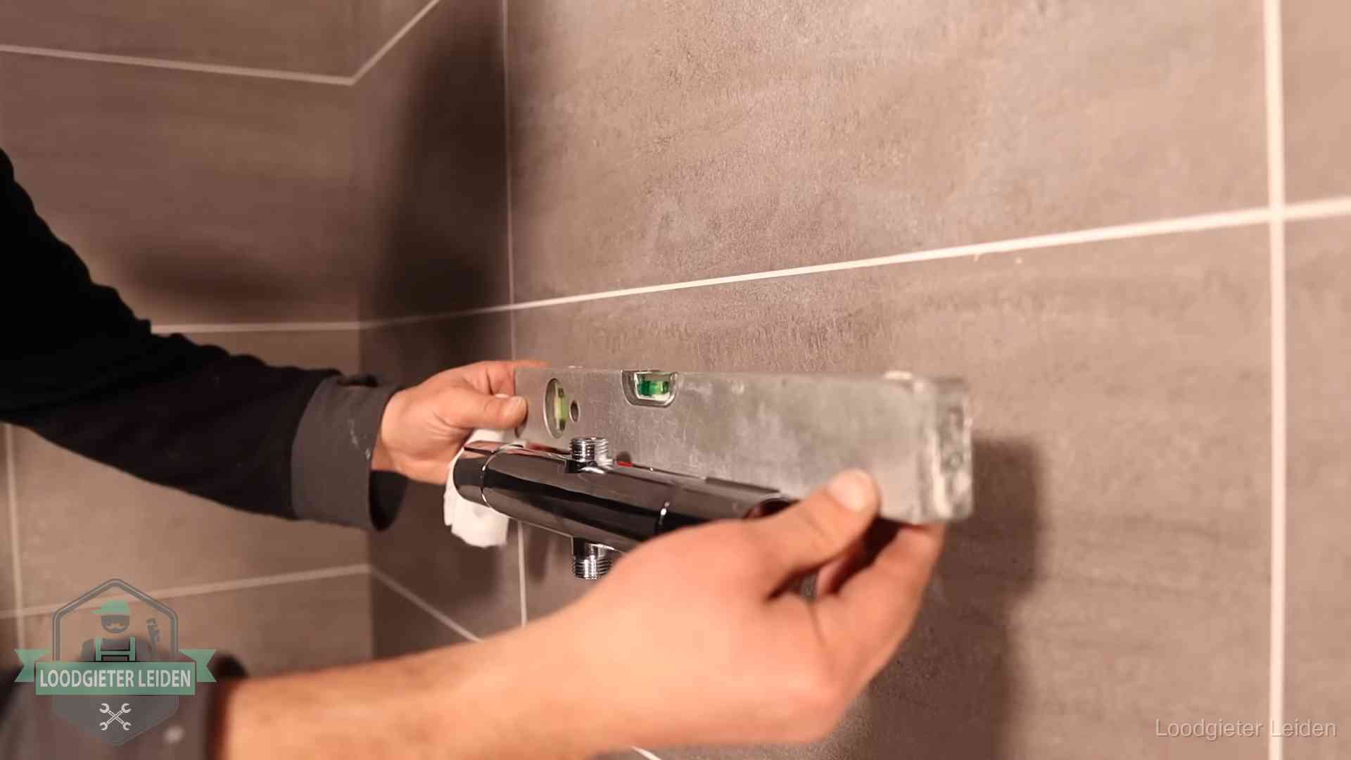 Loodgietersbedrijf voor sanitair in Leiden Loodgieter lijnt een douchekraan uit met een waterpas in een woning in Leiden