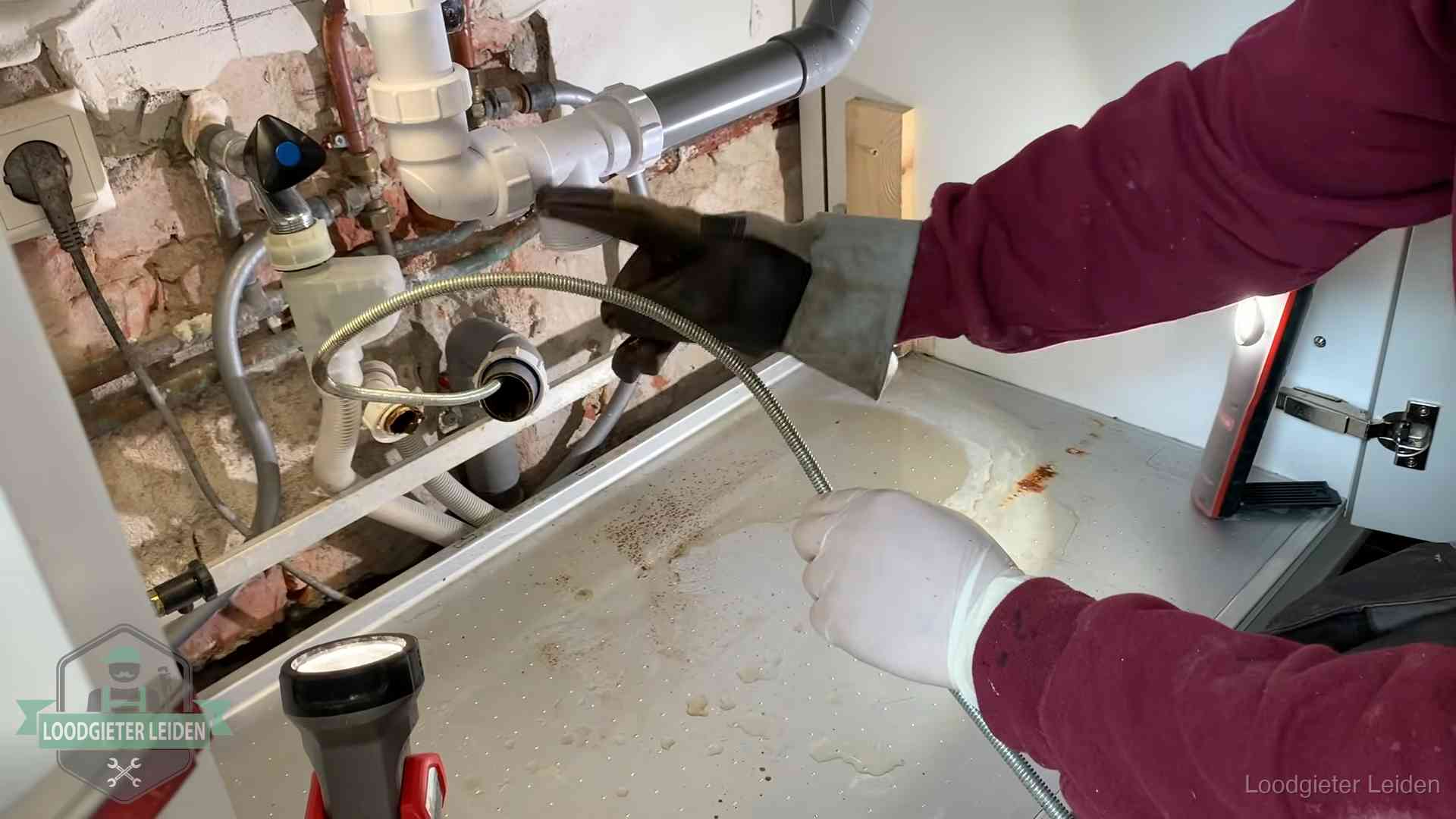 Spiraal of hogedruk in Leiden Ontstoppingsveer gaat in een geopende sifonaansluiting onder het aanrecht in Leiden
