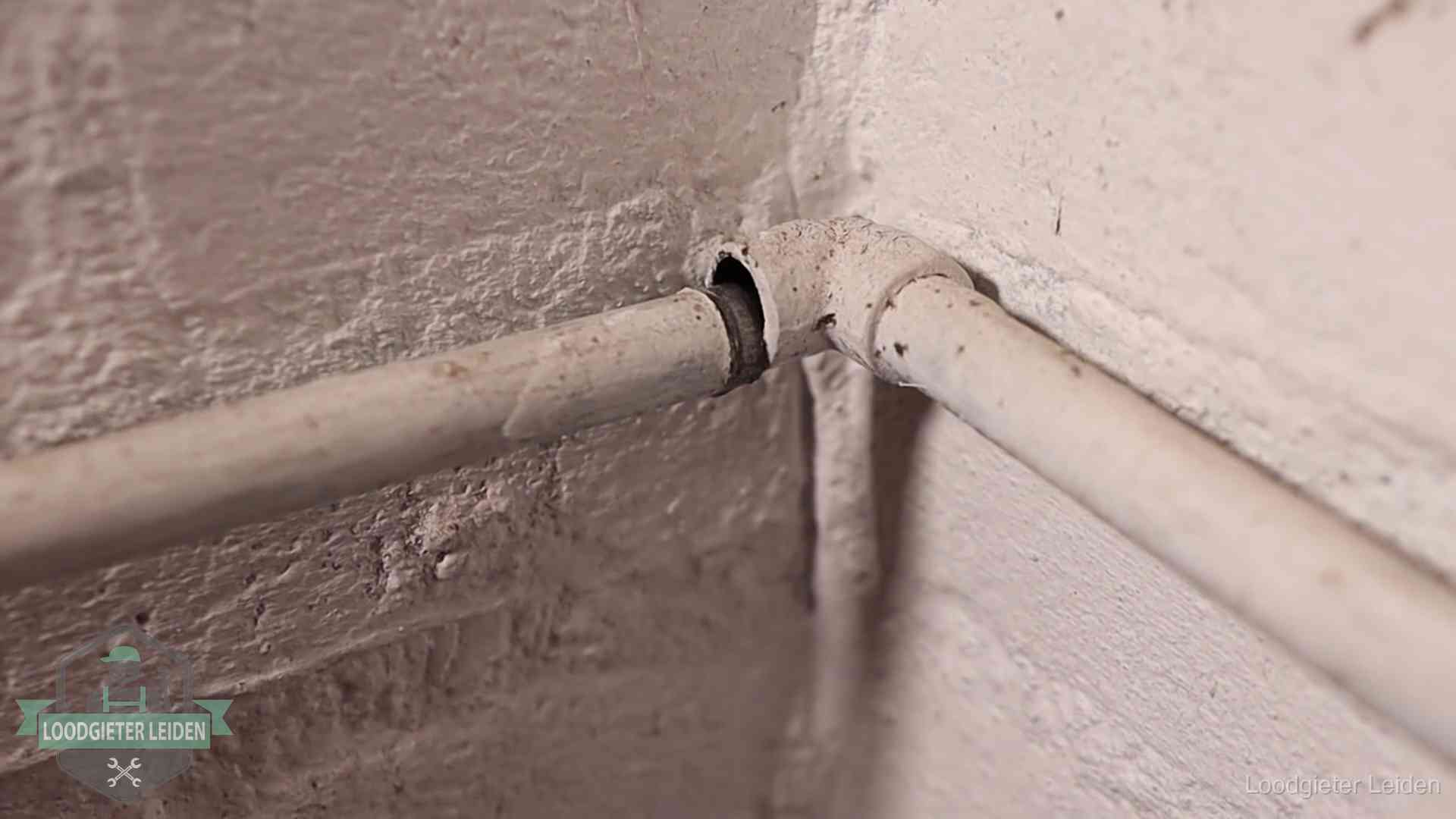 Oude geverfde waterleiding met een losliggende fitting in een woning in Leiden