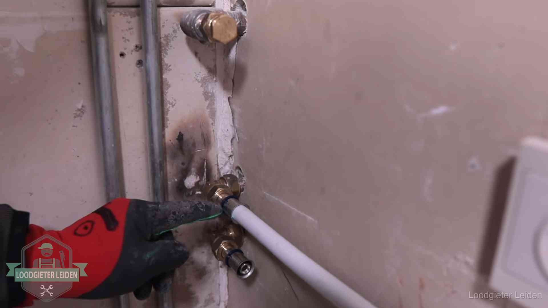 Garantie op loodgieterswerk in Leiden Loodgieter wijst de persfitting op nieuwe muuraansluitingen aan in een woning in Leiden