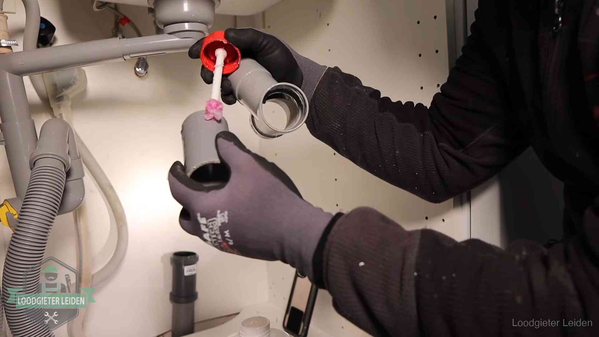 Oorzaak van een verstopte afvoer in Leiden Loodgieter demonteert en reinigt de sifon onder een keukenkast in Leiden
